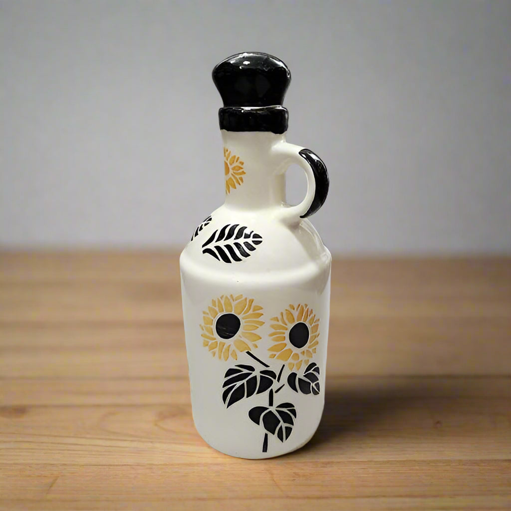 White ceramic oil dispenser bottle with sunflower design on a wooden surface
