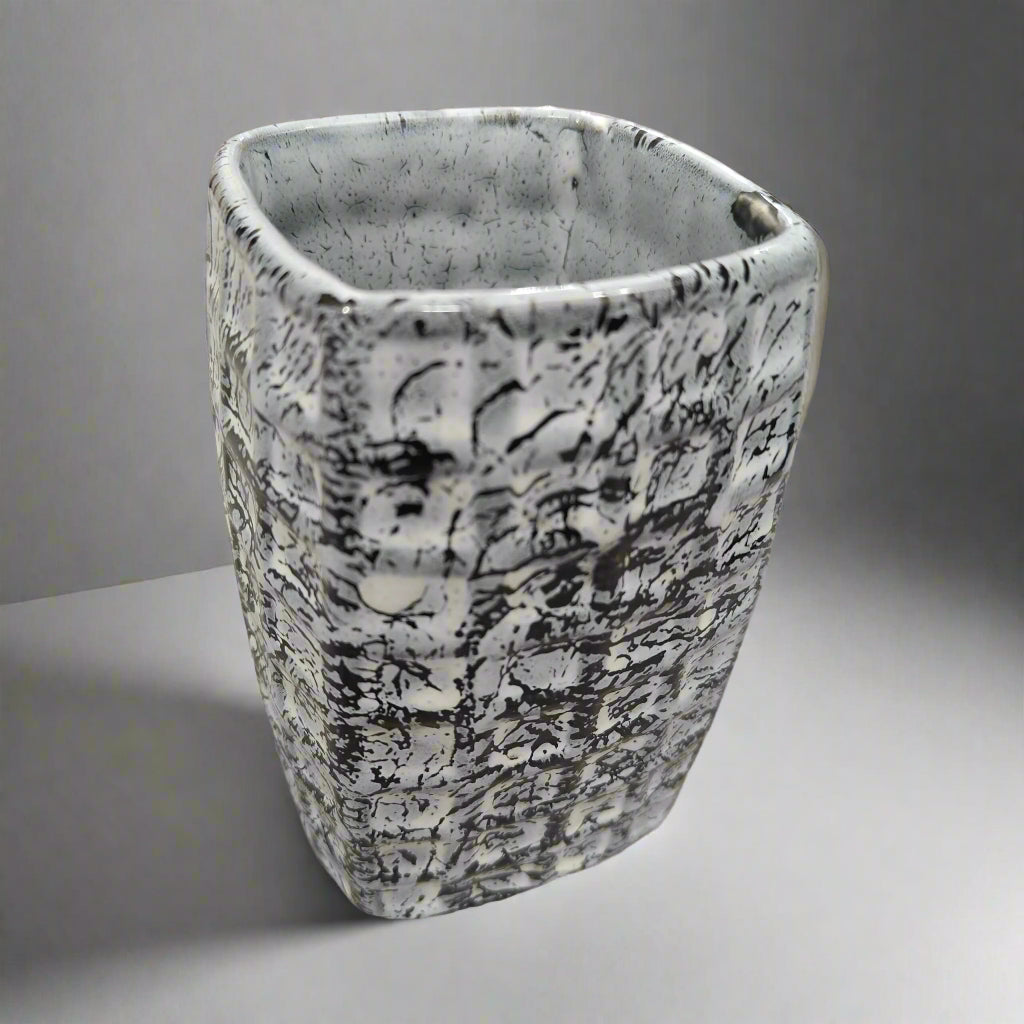 Decorative ceramic vase with black abstract patterns on a marble countertop