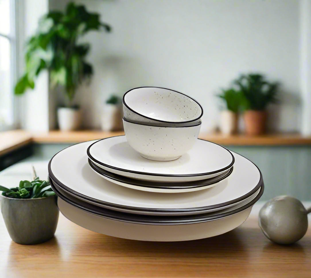 6-piece white ceramic dinnerware set with black border, including plates and bowls, displayed on a dining table with a modern minimalist background