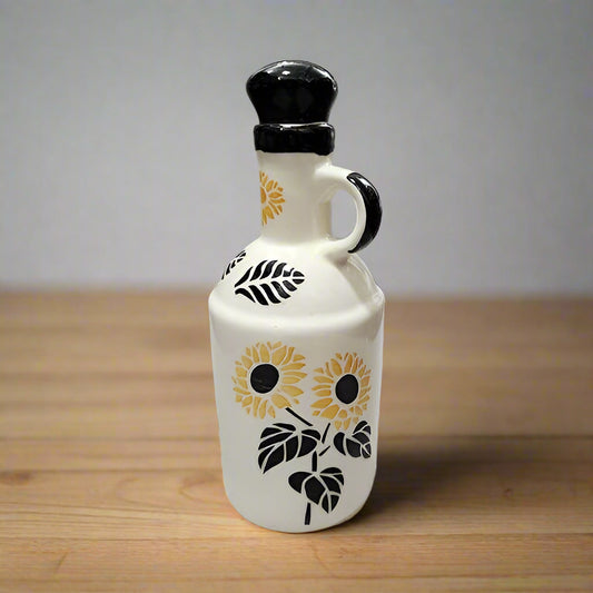 White ceramic oil dispenser bottle with sunflower design on a wooden surface